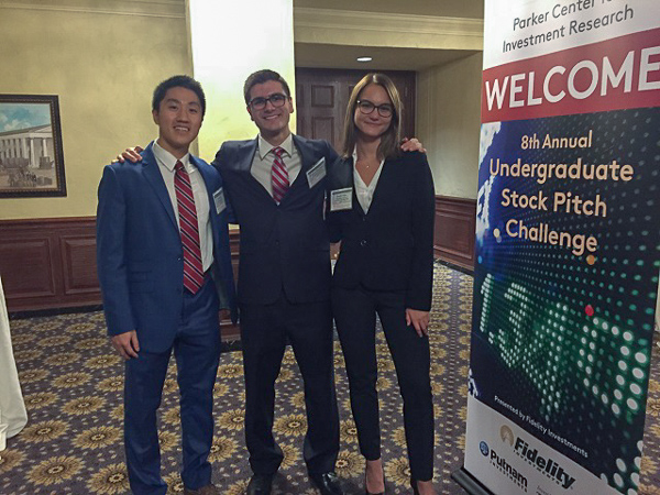 Photo of three students standing in front of a banner