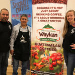 Abner Argueta and Manrique Lopez with Maggie in front of their event sign