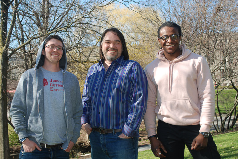 Three men standing outside posing for a photo