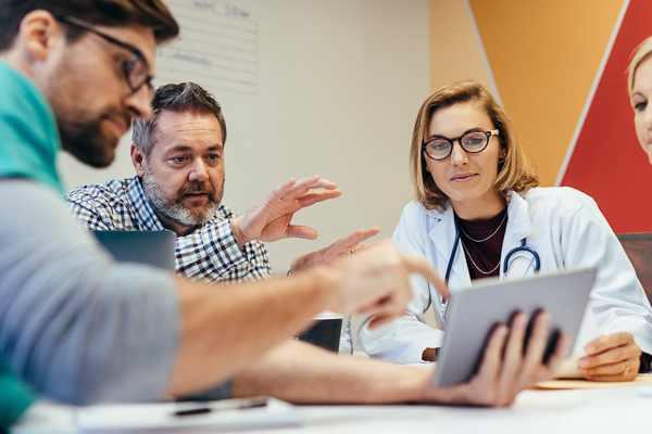 Healthcare professionals gathered around a tablet and table