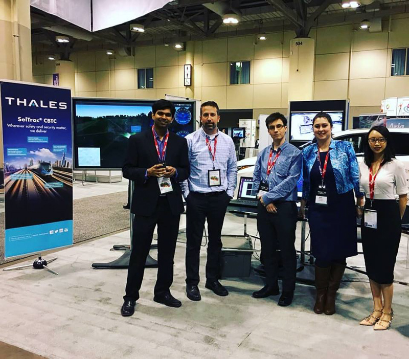 Six people at a trade show with banners in the background