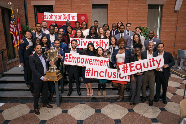 A group of Consortium students stand with their trophy and large signs like #inclusion