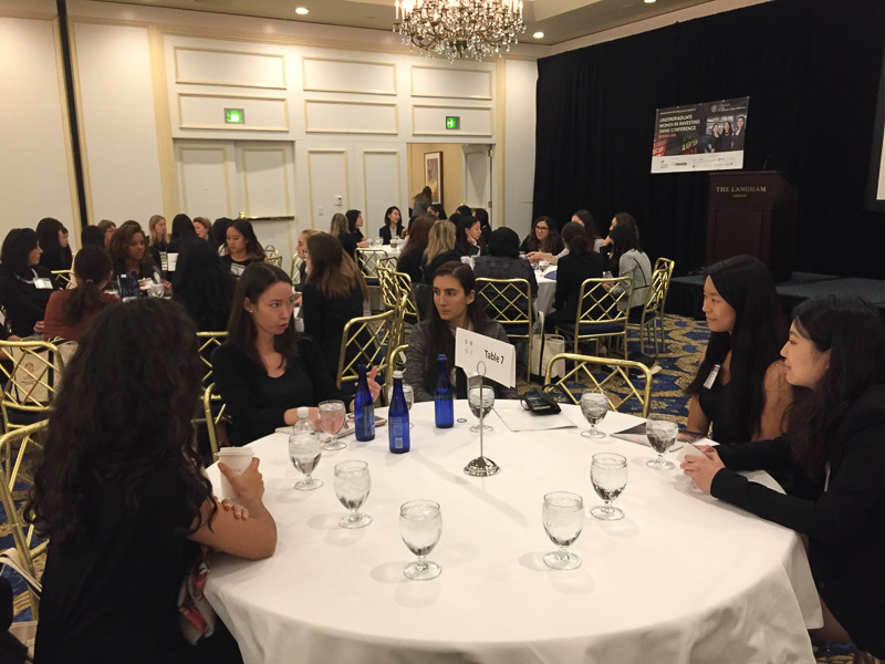 Students sitting around tables networking