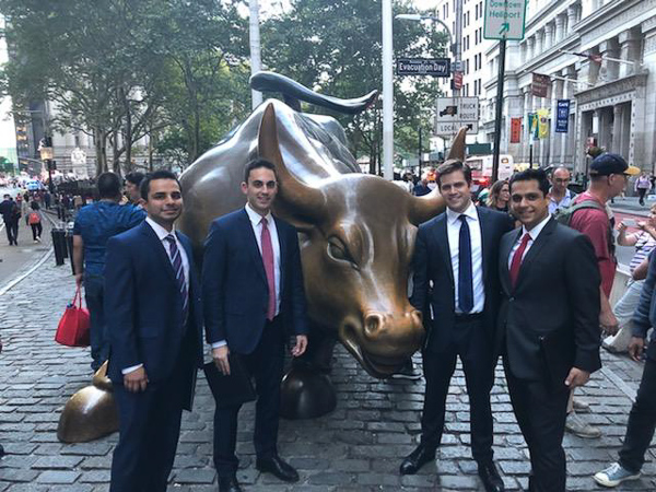 Four students stand next to the Wall Street bull