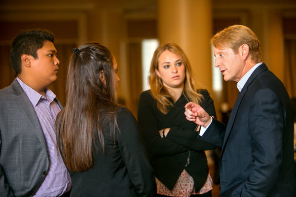 Group of students speaking with a faculty member in a close circle