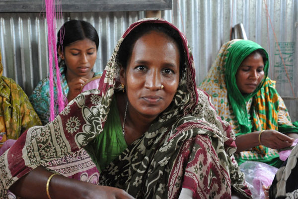 Woman in weaving facility looking into camera smiling