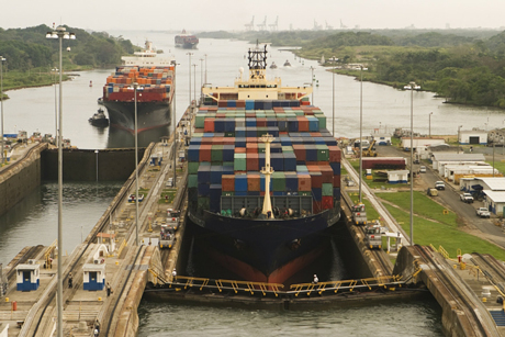 Faraway shot of a loaded cargo ship filled with cargo containers in a lock