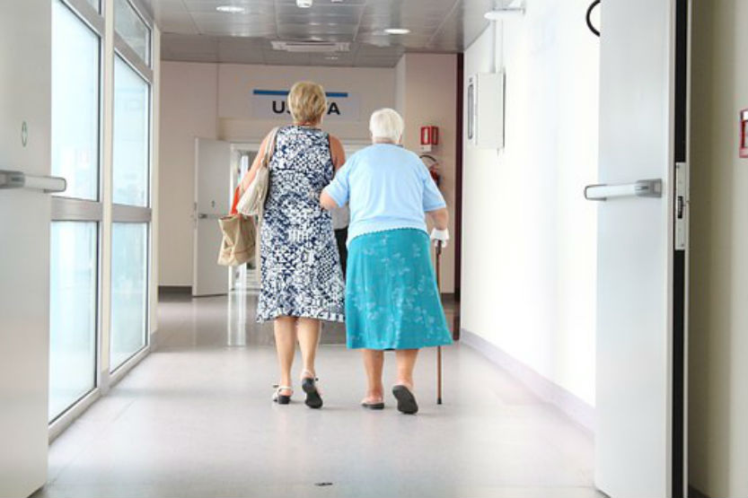 woman helping elderly senior down hallway