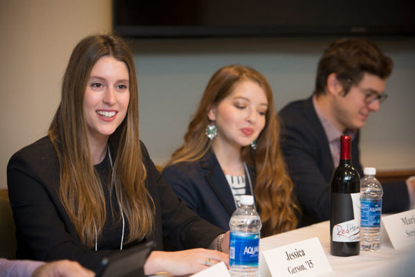 three well dressed students sitting, the first student is smiling and looking at someone not in photo.