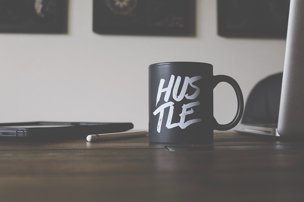 Coffee mug on a desk that says "hustle"