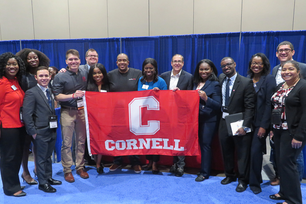 A group standing with a Cornell banner
