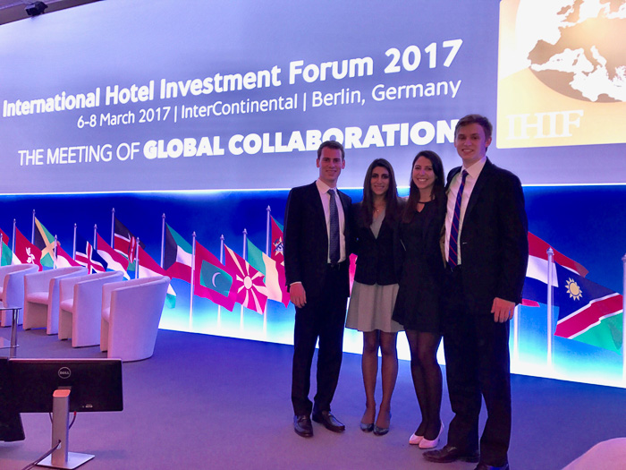 Four students stand in front of a presentation screen