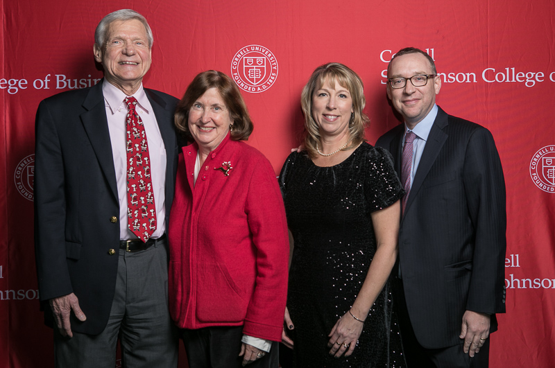 The deans on their wives pose for a photo in front of the Cornell University step-and-repeat background