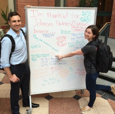 Austin and Shannon Boyle in front of a whiteboard that reads "I'm thankful for Johnson Partners/Families because..."