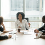 Female boss leading diverse corporate team meeting in boardroom