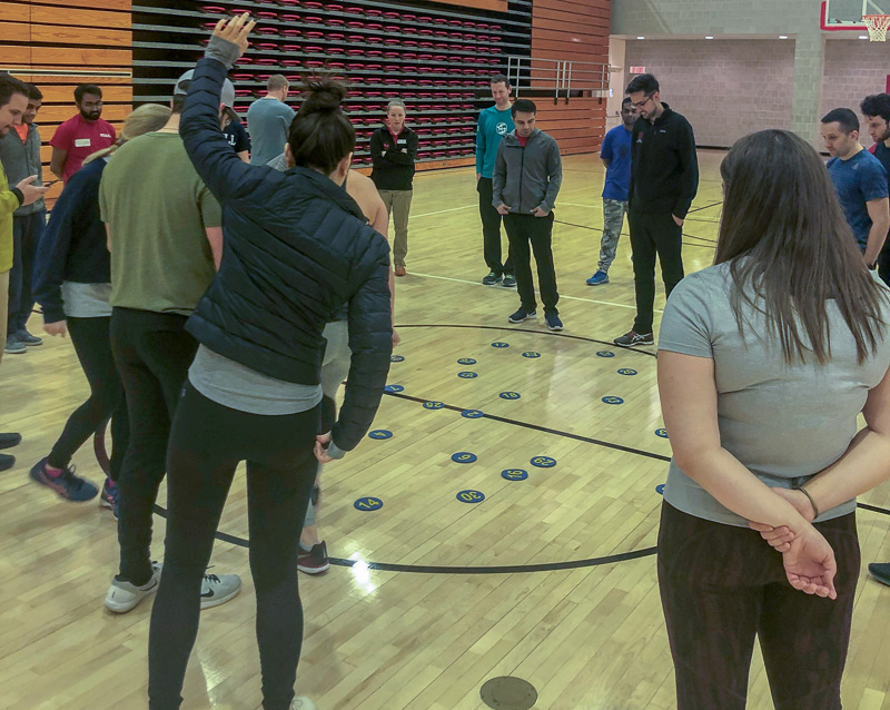 Students stand around dots on the gym floor