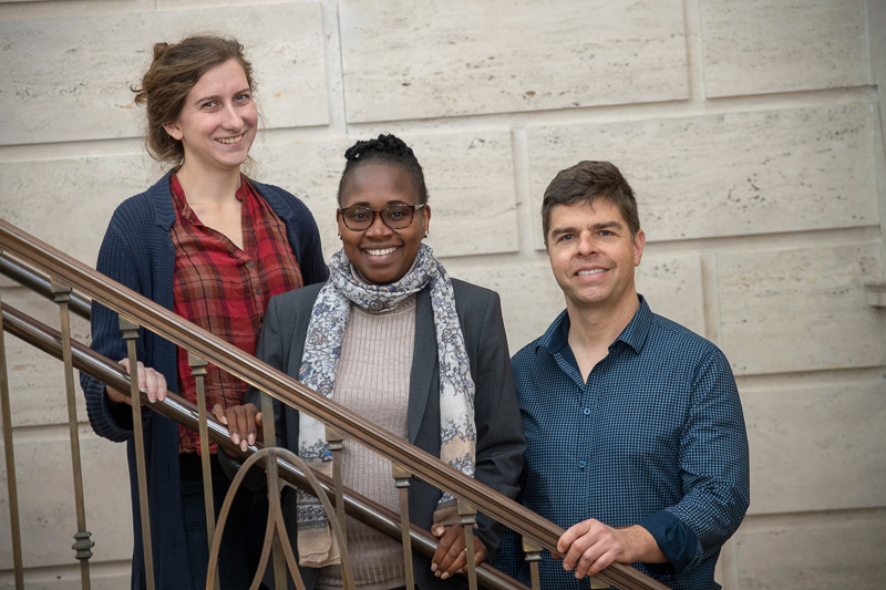 Margaret, Colleta, and Garrick stand on a staircase