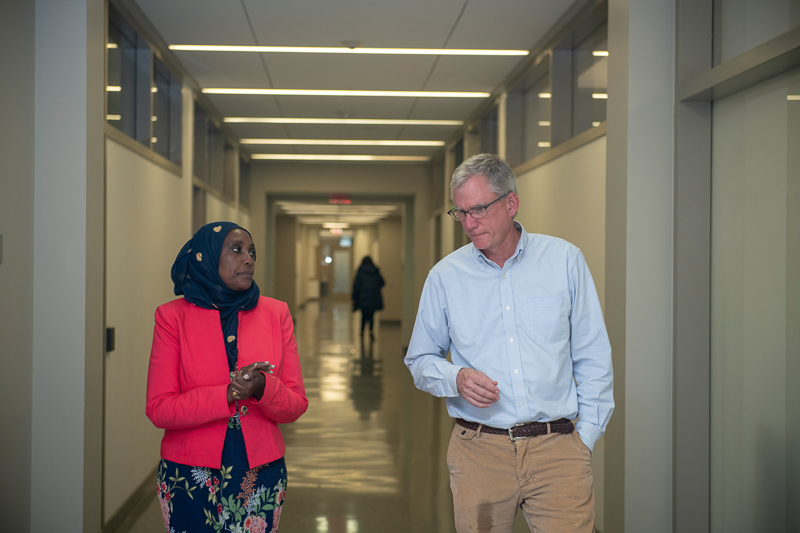 Mumina and John walk down a hallway