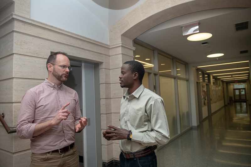 Brian and Soumalia talk in a hallway