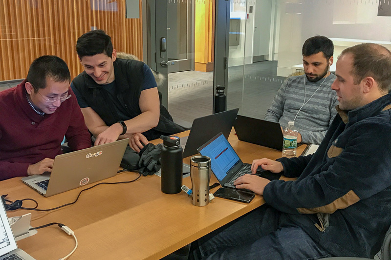 A group of students works at a table with computers