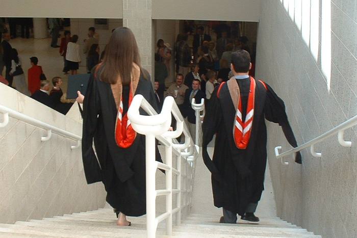 Kara and Matt walk down the stairs headed to convocation