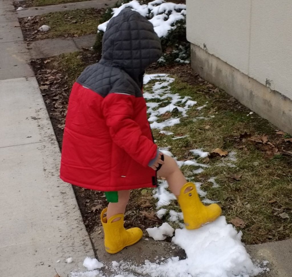 Gabe Sudduth's son plays in the snow, despite wearing an outfit that does not match Ithaca's winter temperatures.