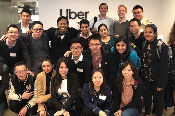 A group of students stands in front an Uber sign