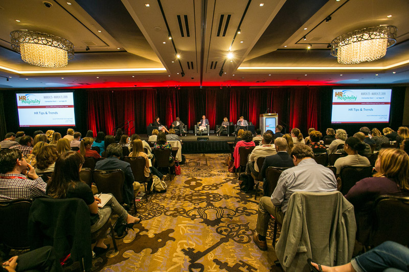 A panel speaking to a crowded ballroom 