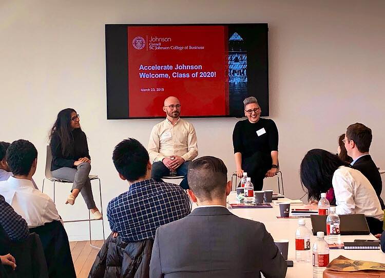 Three panelists speak at the front of the classroom