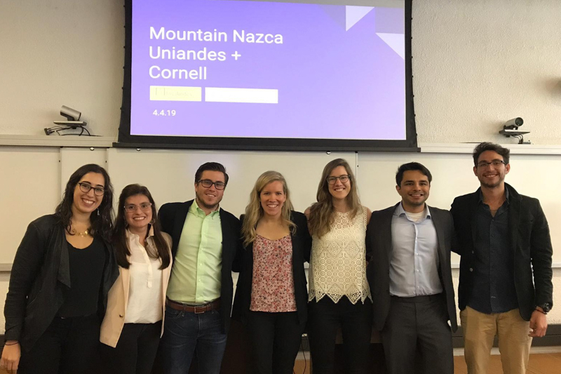 Small group standing in front of a television monitor that says Cornell + Uniandes