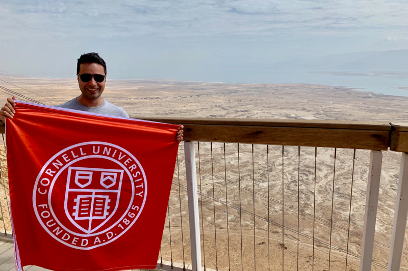 Sanchit Mall holding a Cornell banner overlooking Jerusalem