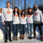 Group of five students stands in the snow