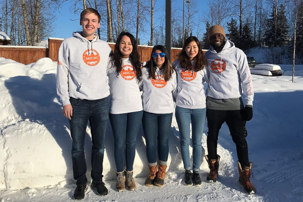 Group of five students stands in the snow