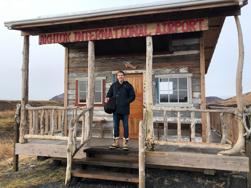 Colin standing in front of a small building that says "airport"