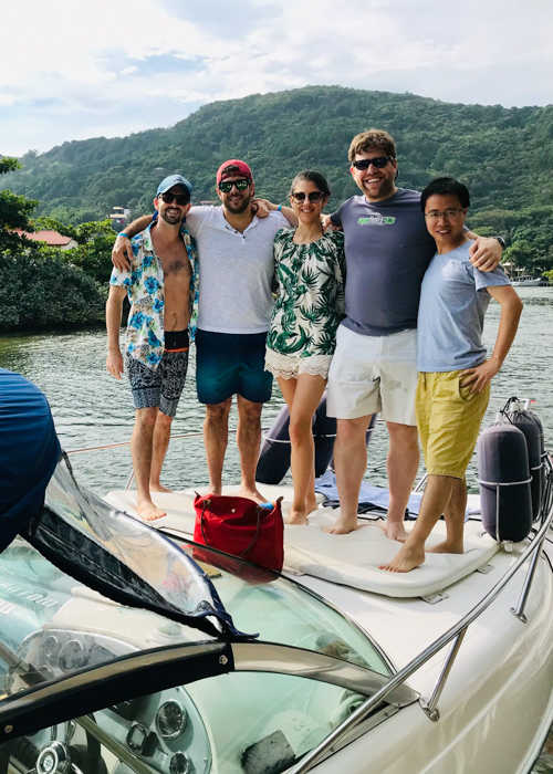 Five people standing on top of a speedboat