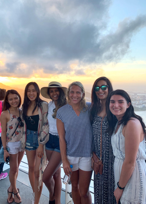 A group poses with a sunset behind them