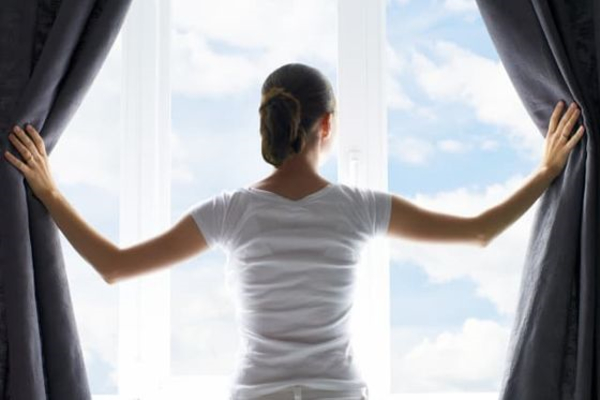 Person opening the curtains to reveal a window