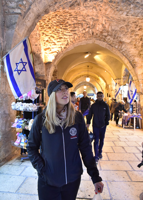 Katie walking though a building with Israel's flag in the background