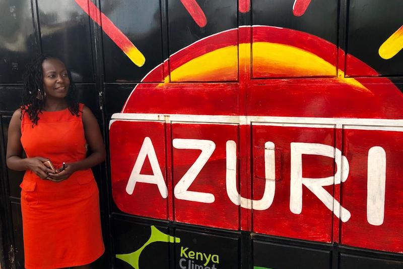 Tei Mukunya standing next to a painting of Azuri Health's logo