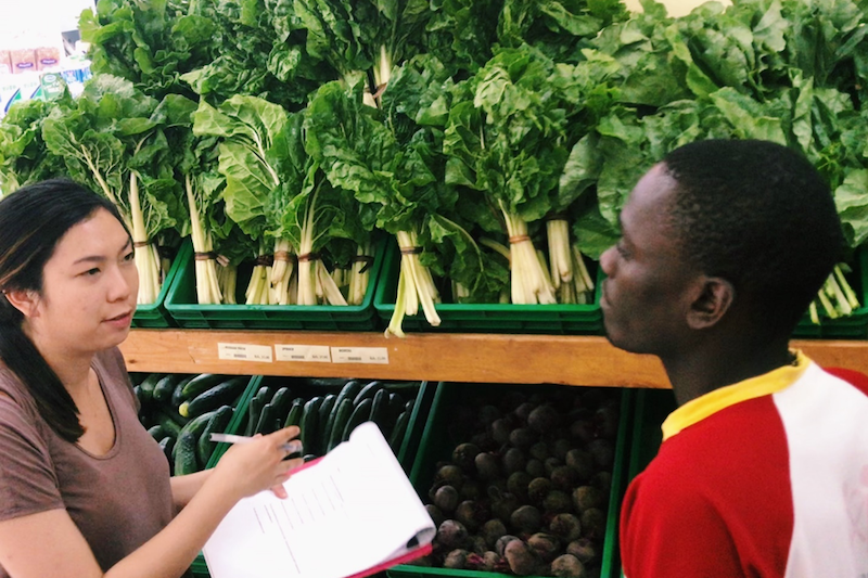 Student surrounded by vegetables in the supermarket