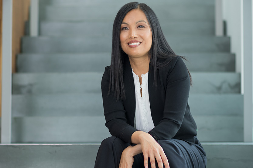 Maggie Chan Jones, smiling, sitting on a staircase