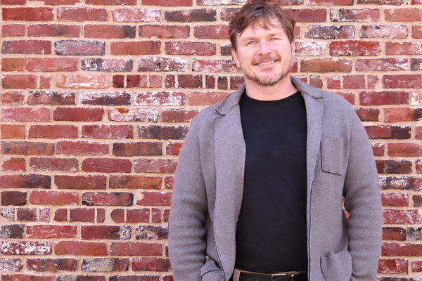 portrait of Scott Yewell standing in front of a brick wall