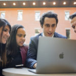 MPS students in discussion looking at a laptop