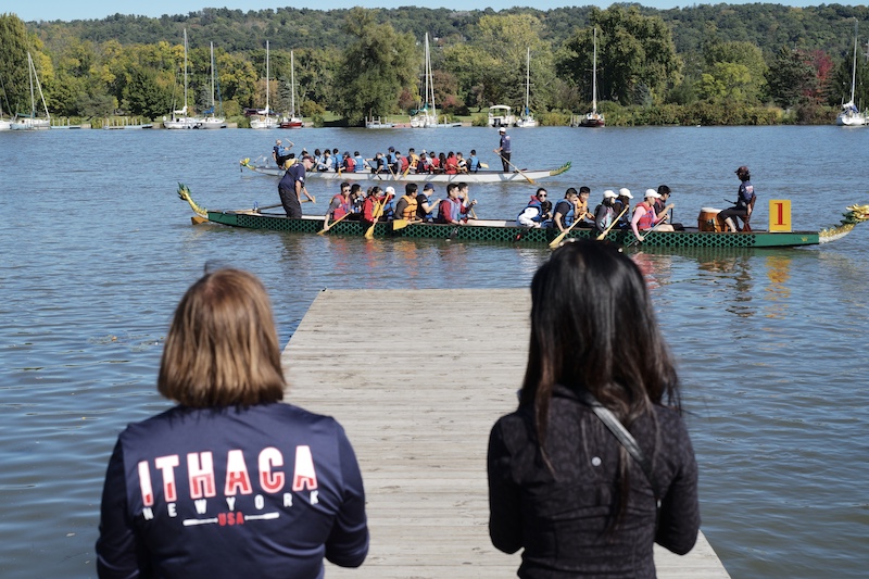 Two women watch the boat races from the dock 