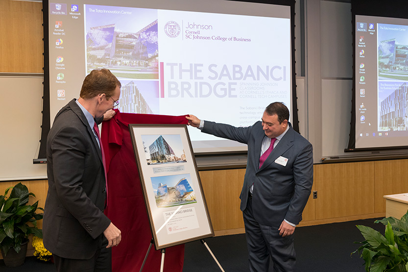 Dean Mark Nelson and Demir Savanci unveiling a framed, commemorative gift of appreciation that includes photos of the Tata Innovation Center and the Breazzano Family Center for Business Education.