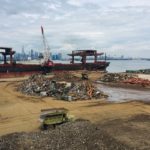 Scrap metal pile with machines and the NYC skyline