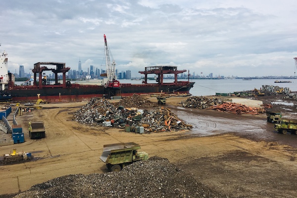 Scrap metal pile with machines and the NYC skyline