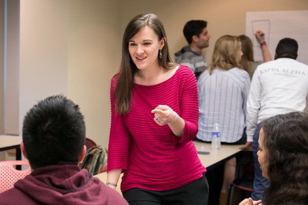 Prof. Kristina Workman speaks to two students in class