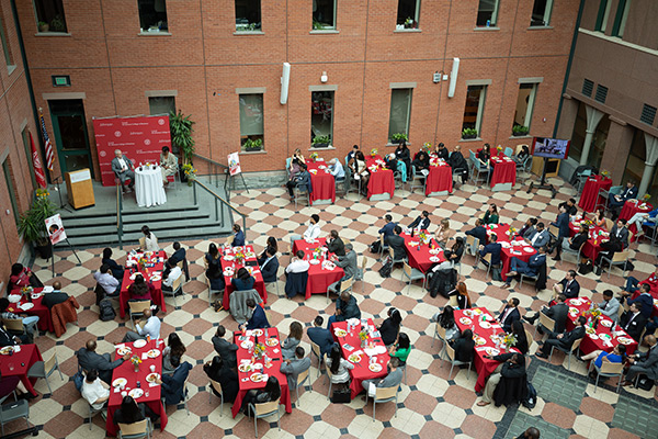 Sage Hall's Dyson Atrium shot from pverhead, showing a room filled with tables and Larry Ruff and Cynthia Saunders-Cheatham seated and speaking on stage