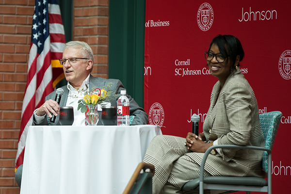 Larry Ruff, MBA ’82, and Cynthia Saunders-Cheatham seated at a table on stage in Sage Hall's Dyson Atrium